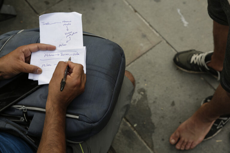 Ismail, voluntario de ‘Linea d’Ombra’, escribe en un papel los diferentes caminos para indicar a las personas en movimiento la manera de continuar con la ruta migratoria una vez que logran llegar a la plaza de ‘La libertad’, en Trieste (Italia). Eduardo Oyana