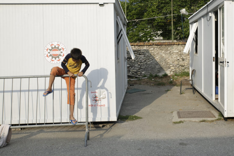 Un niño juega subido en una valla en el refugio ‘Fraternitá Massi’ (Oulx, Italia). Eduardo Oyana